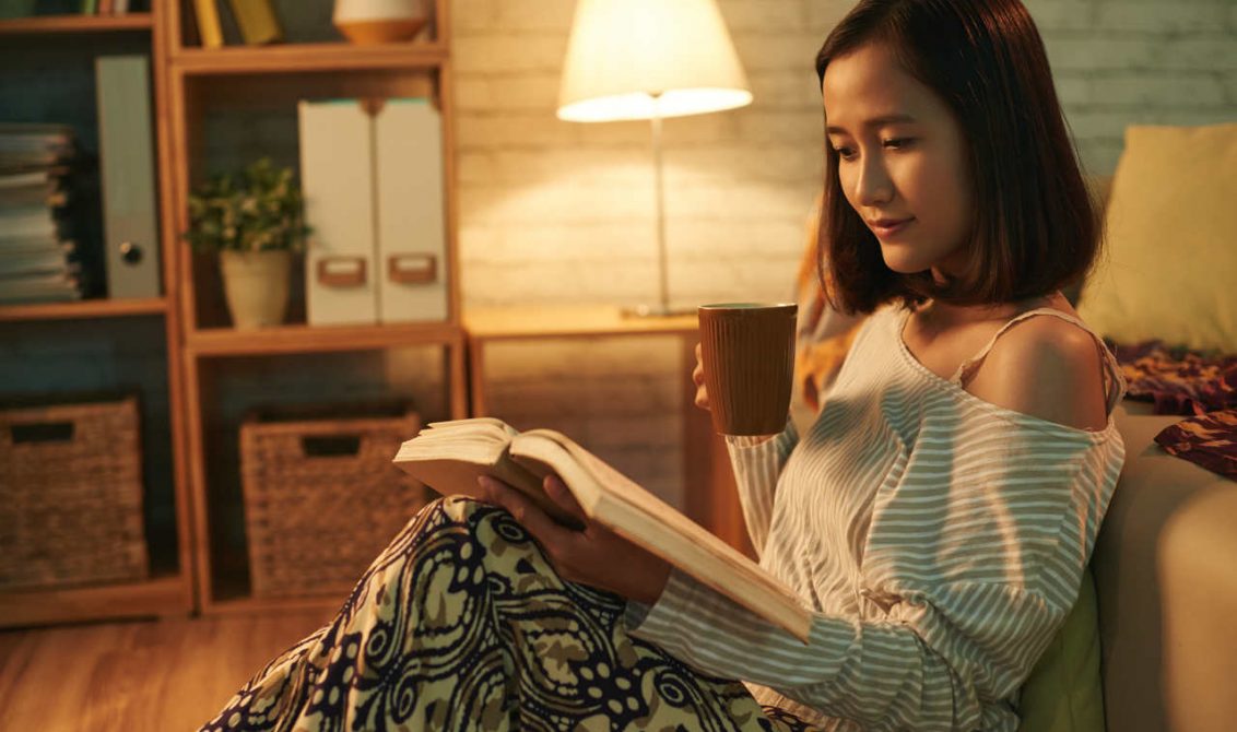 Koltukta oturup kitap okuyan genç bir kadın
